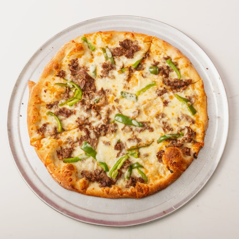 A whole pizza with white cheese, ground meat, and green bell peppers on a metal tray.