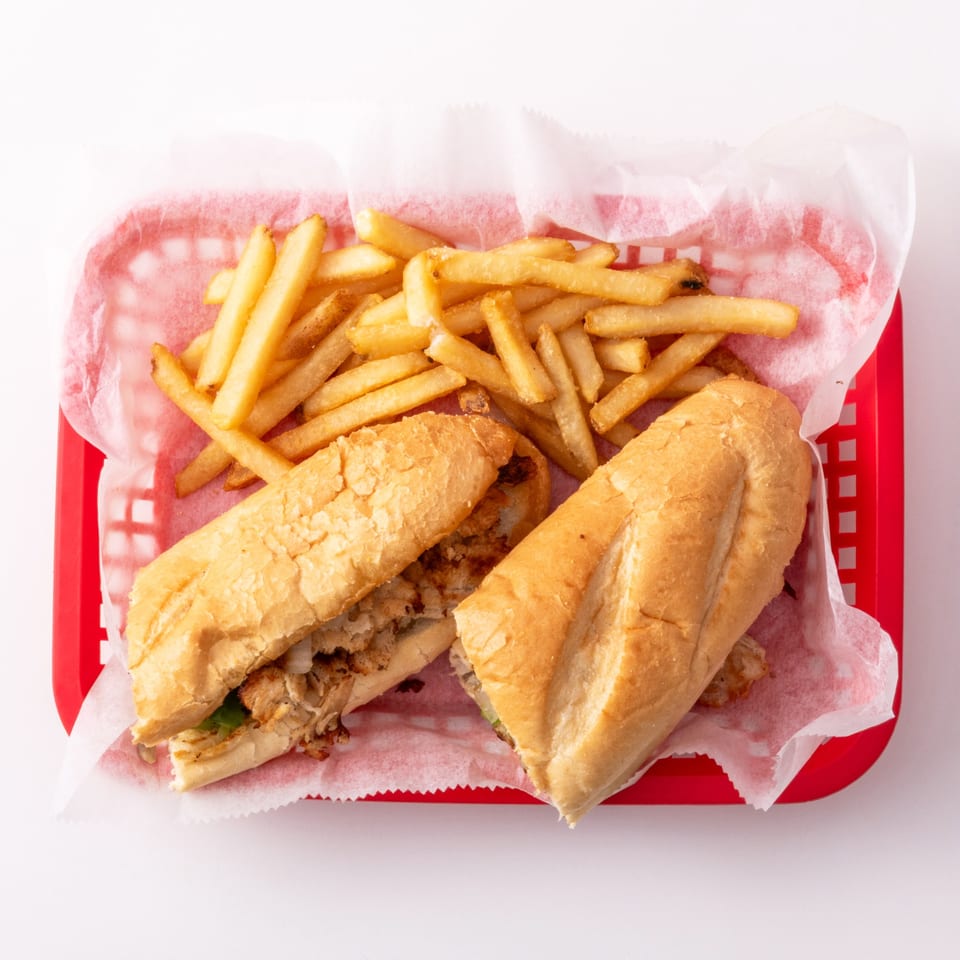 Two chicken sandwiches and a pile of golden french fries in a red plastic basket.
